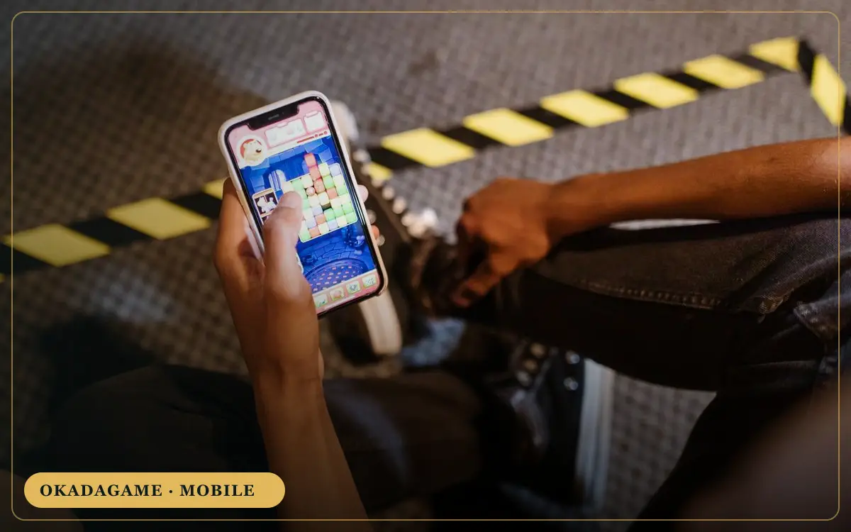OKADAGAME mobile – player holding a smartphone game